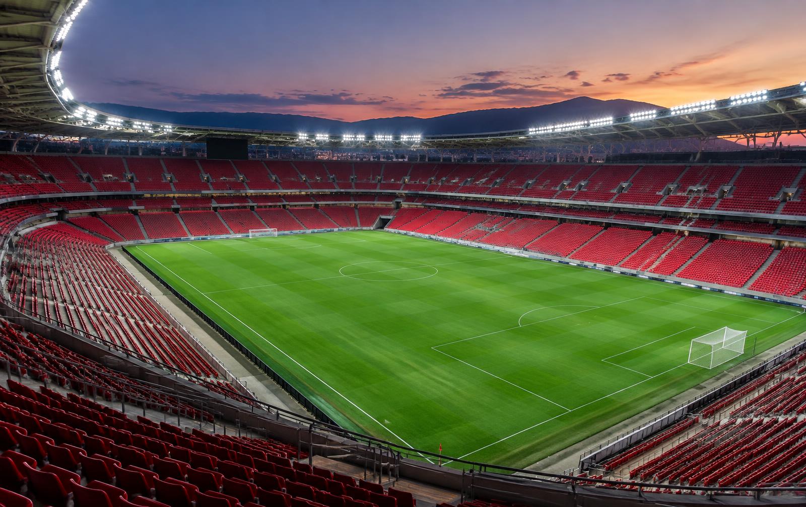 Estadio de fútbol vacío al atardecer con los focos encendidos