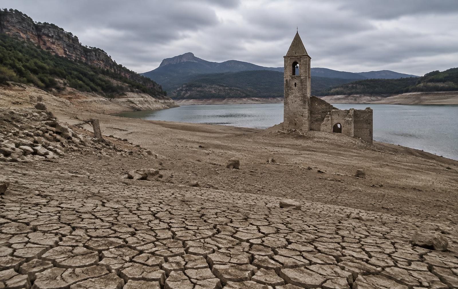 Embalse con el lecho agrietado y las ruinas de un campanario al descubierto